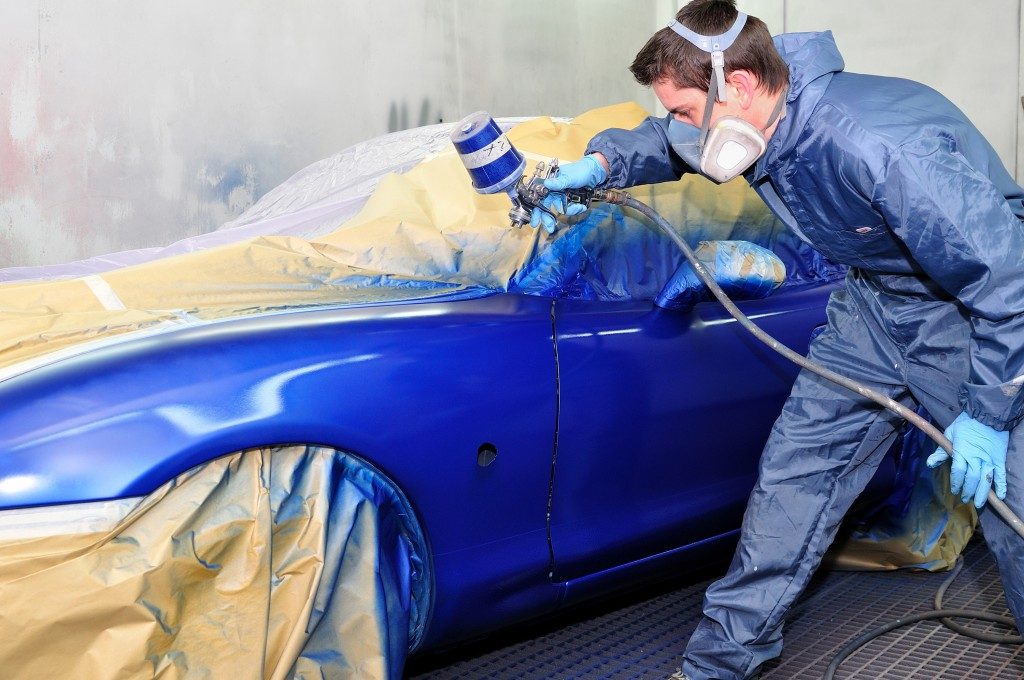 Worker painting the car blue