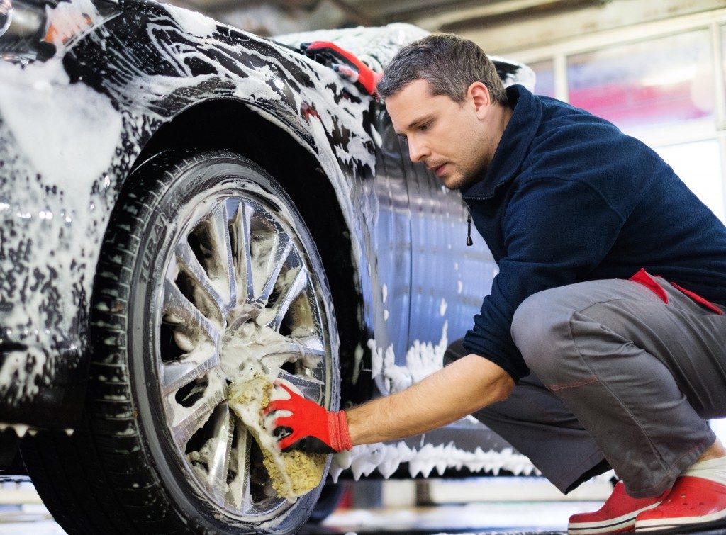 Man cleaning the car wheel