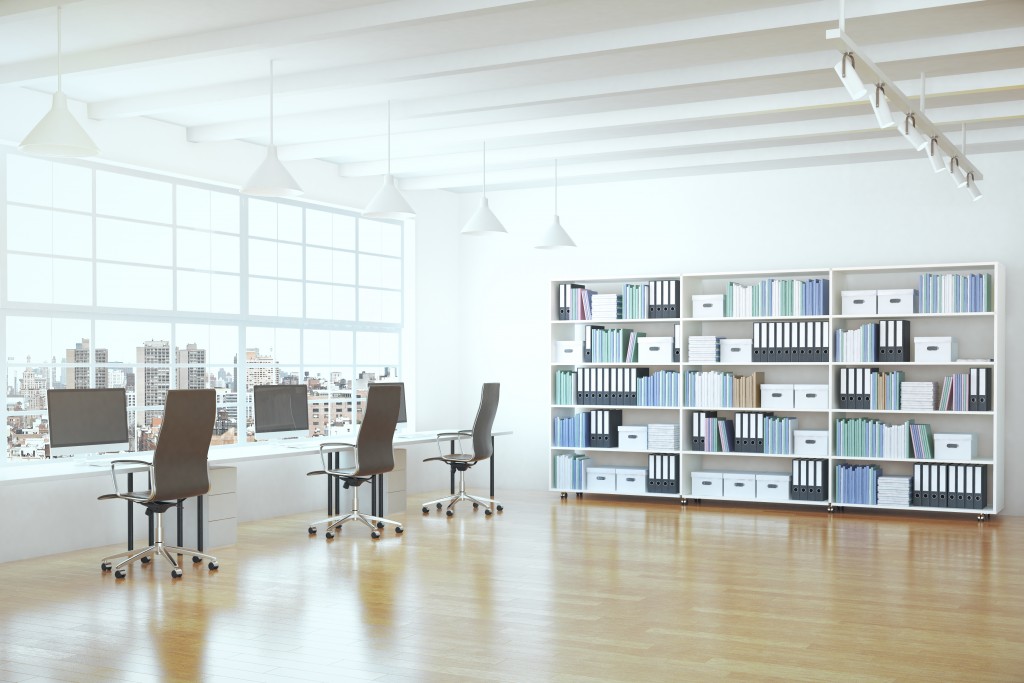 spacious workplace with wooden flooring and desks facing the window