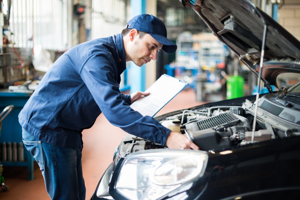 repairman checking car engine