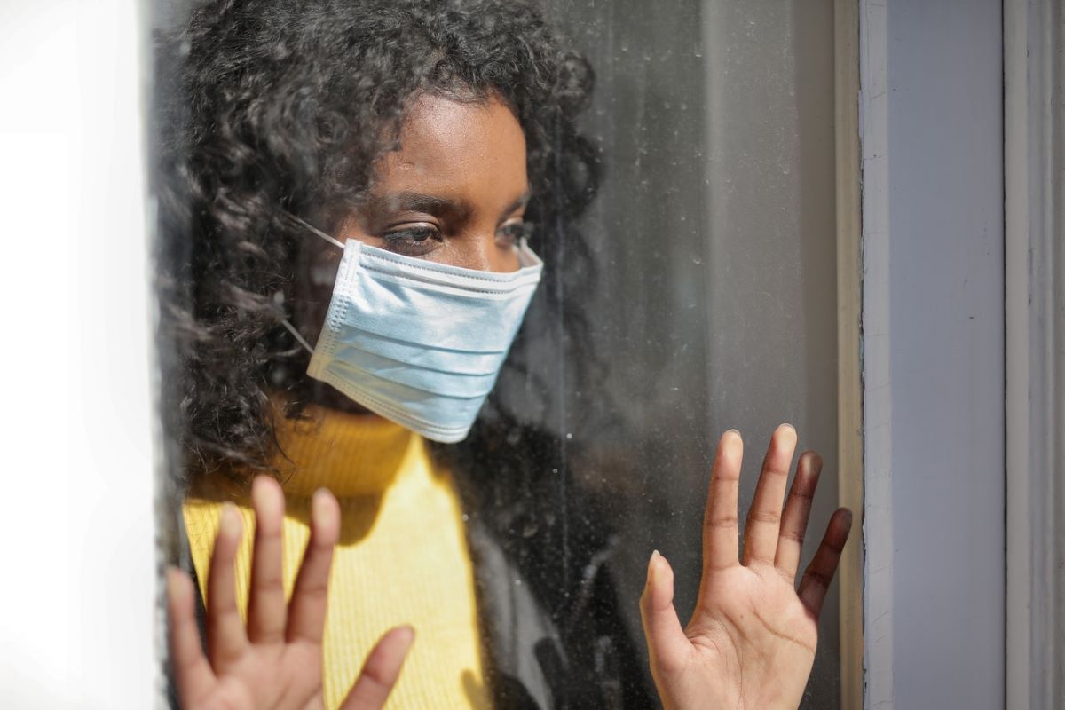 woman wearing facemask staring out the window