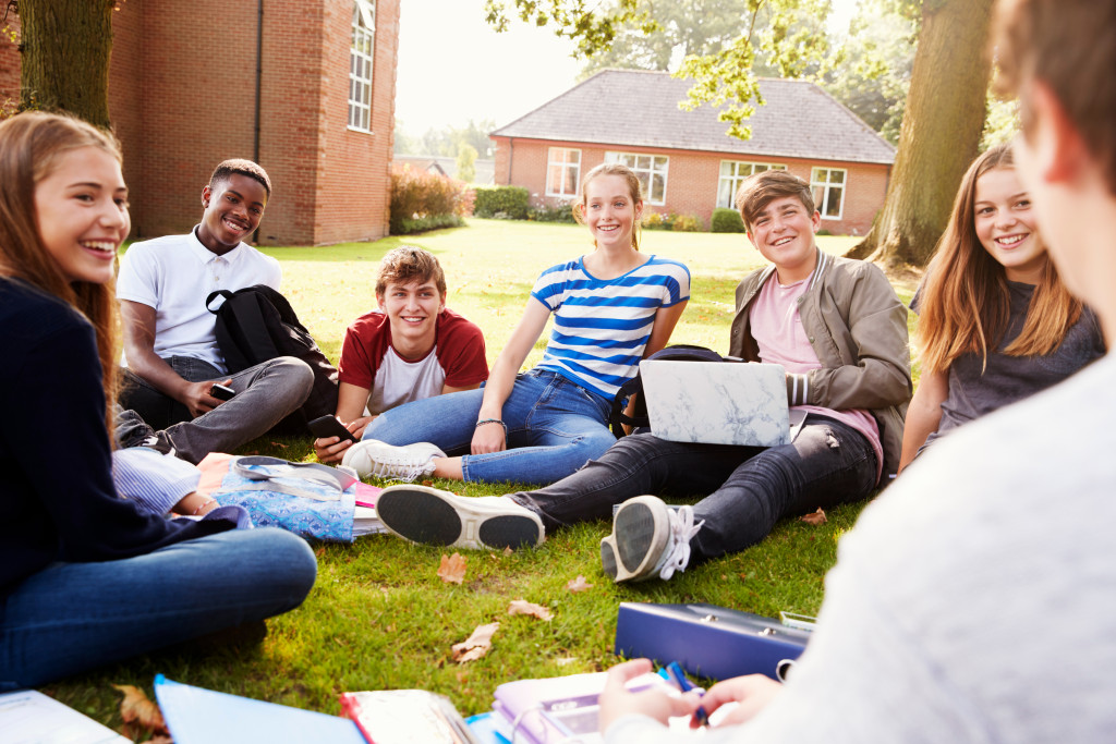 Group of students sitting in a circle on the grass in their school grounds