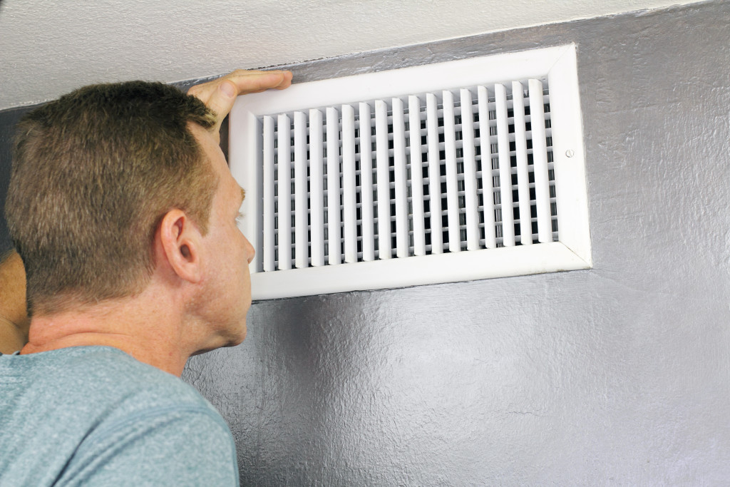 man checking air vent of his house