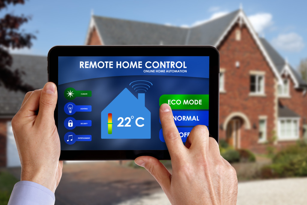 a hand holding a tablet and controlling his home's temperature using it